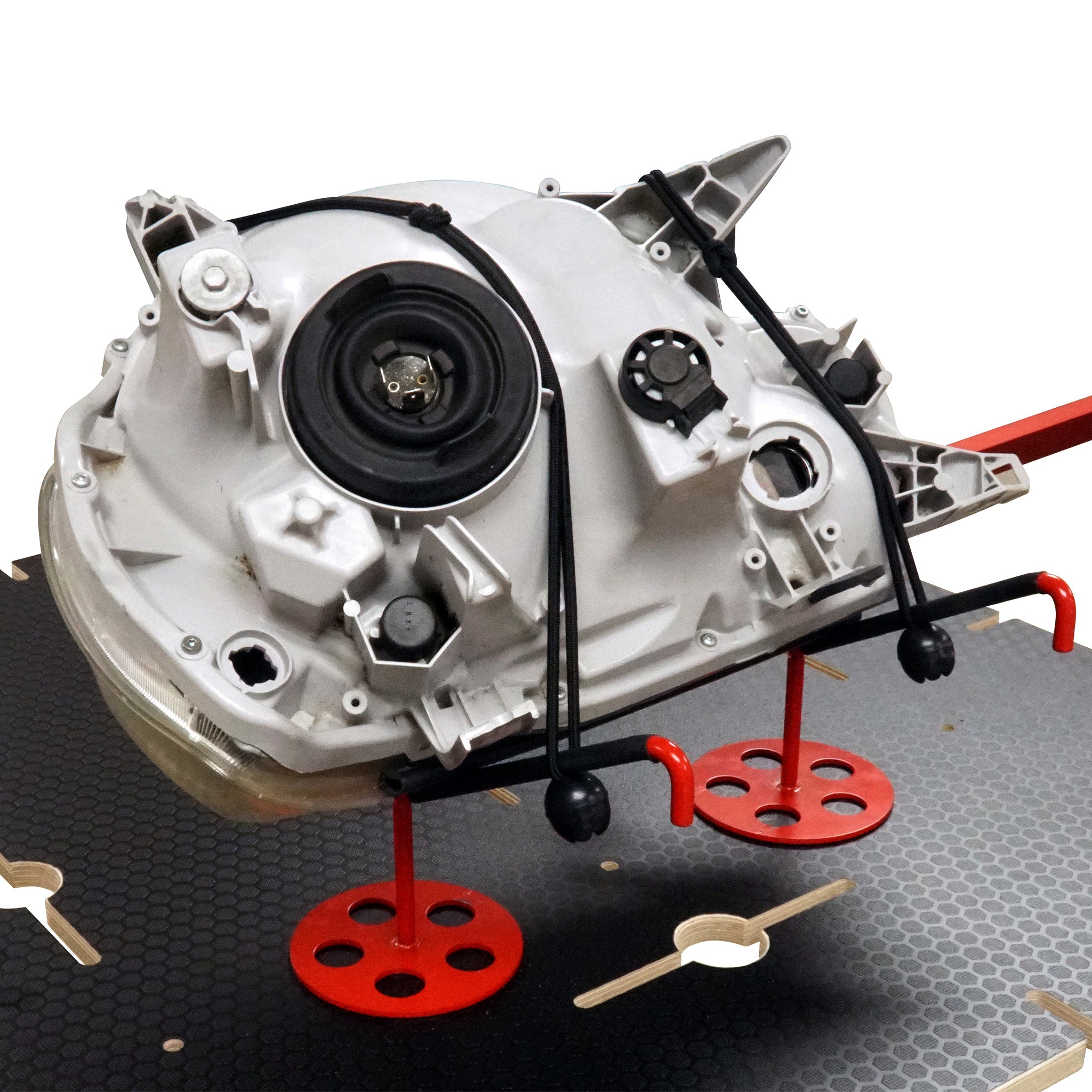 Headlight sitting in cradles on top of the Plastic Repair Workstation, secured by bungees