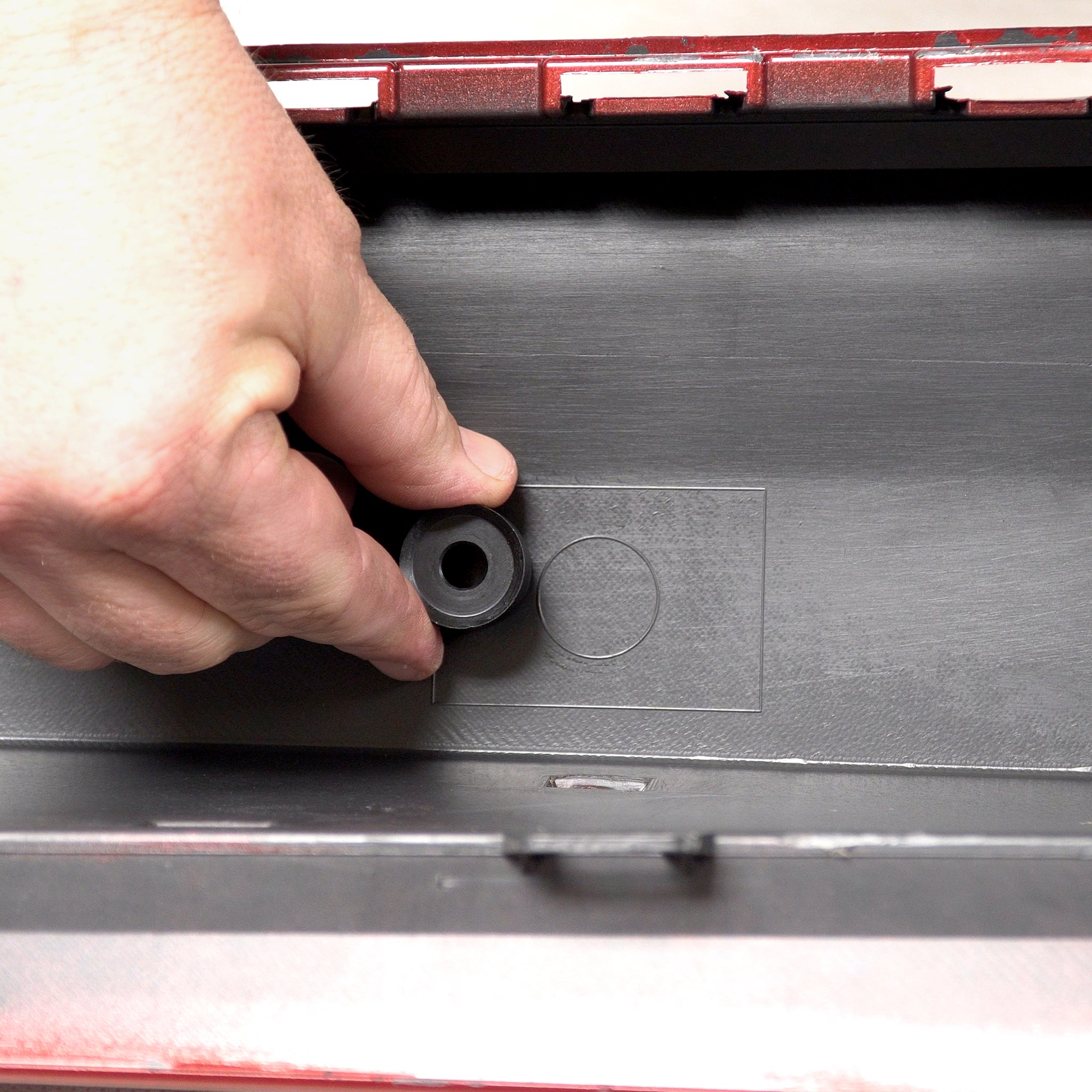 Demonstrating the size of the sensor hole cutter next to the marking for a new hole on a bumper cover