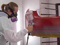 A man spraying a topcoat on a bumper.