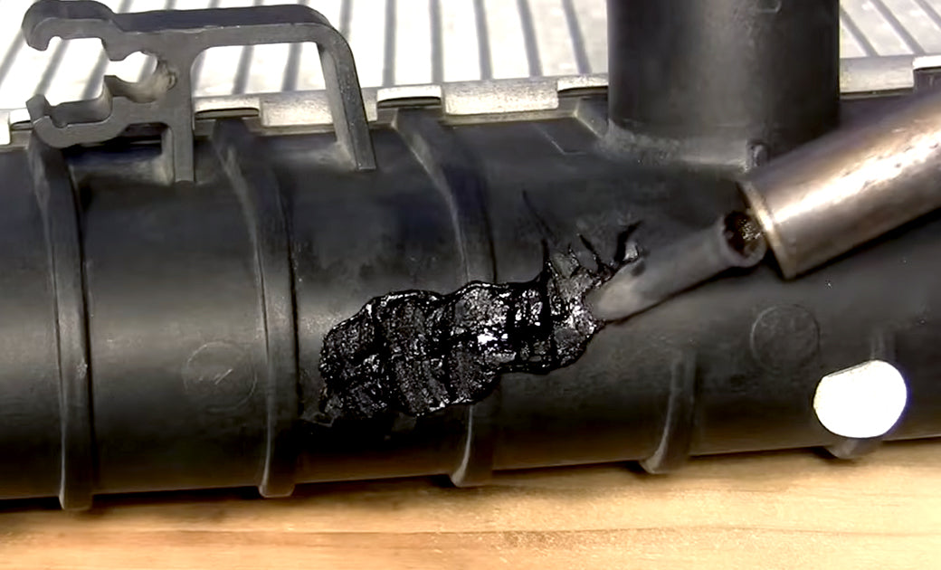 An airless plastic welder smoothing a weld on a radiator