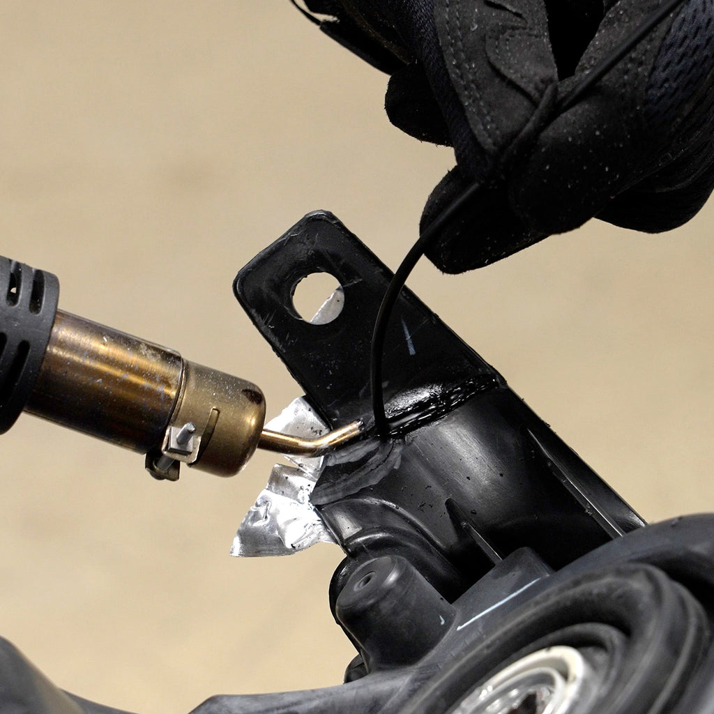 A headlight tab is being welded with the hot air plastic welder and polypropylene welding rod