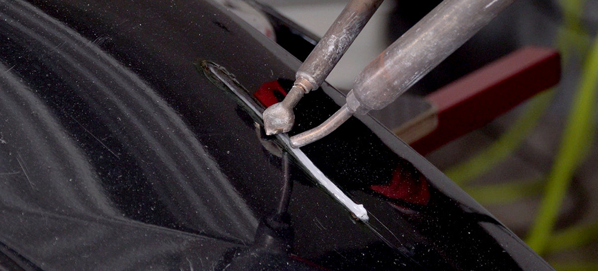 Smoothing a plastic weld using the flat welding tip while the nitrogen welder reheats the weld.