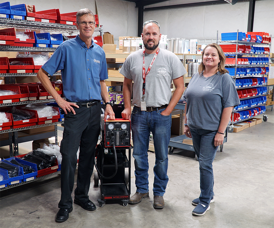 Two men and a woman standing beside a 6057 nitrogen plastic welder