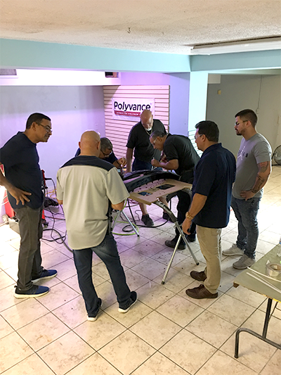 A group of men watching two other men use the nitrogen plastic welder.