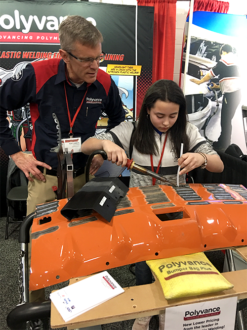 A young lady welds with the nitrogen plastic welder while Kurt watches and guides her through it.