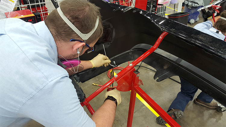 A competitor using the nitrogen plastic welder to make a weld on a bumper.