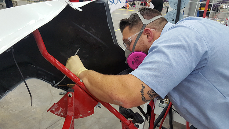 A competitor using the nitrogen plastic welder to make a weld on a bumper.