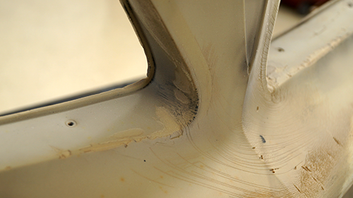 Detail of worn spots on the front bumper after the paint has been sanded off.