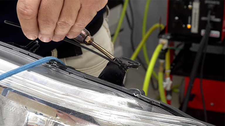 Welding a headlight tab with a nitrogen plastic welder and round polypropylene welding rod