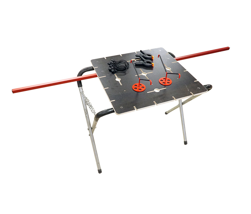 The Bumper Mate 3 main photo shows a black tabletop with two red metal poles sticking out. The tabletop has holes and sections cut out. On top of the table sits bungees and clamps. There are two headlight cradles inserted into holes in the tabletop.