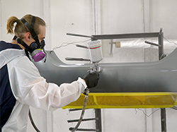 A man spraying Bumper & Cladding Coat Adhesion Primer onto a bumper