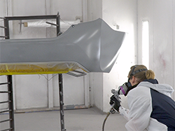 A man spraying a small spot on a bumper